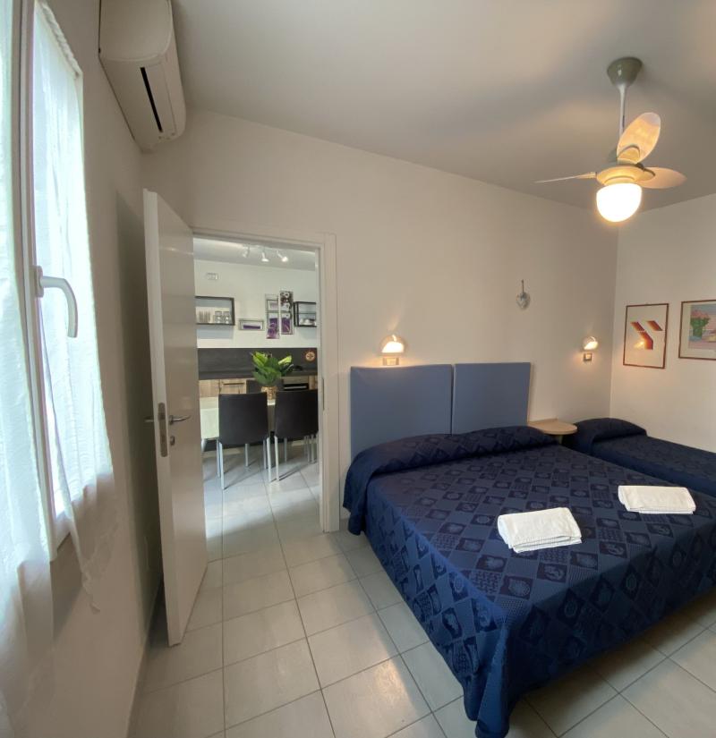 Camera da letto con due letti, ventilatore e quadri alle pareti.