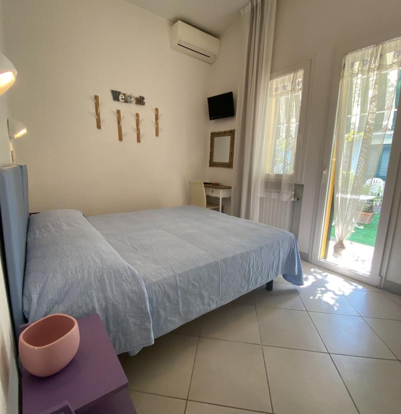 Camera da letto luminosa con letto, TV e aria condizionata.