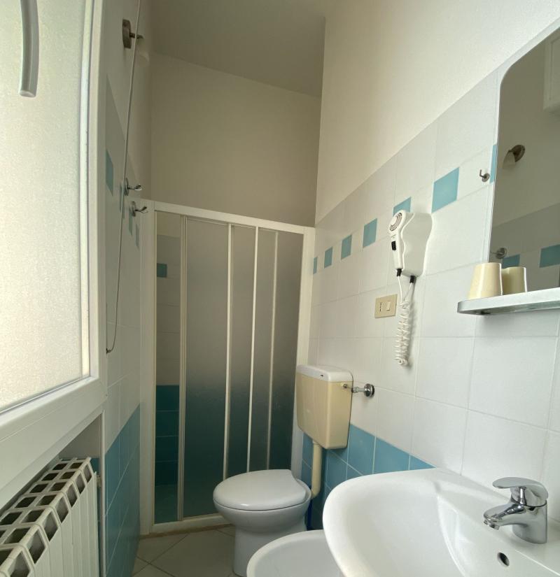 Bagno con doccia, lavabo, WC e piastrelle azzurre.